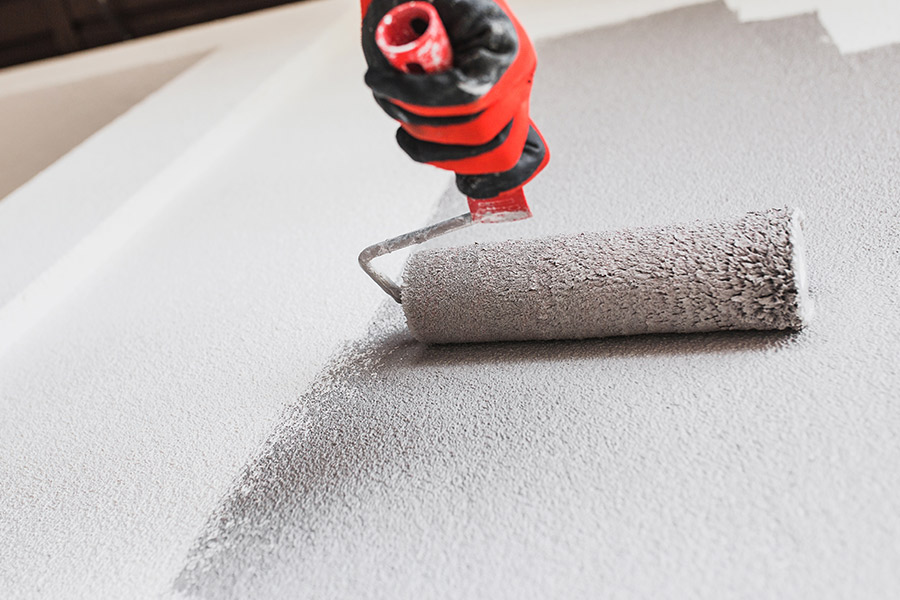 contractor hand with glove and paint roller painting residential property wall close up palm beach fl